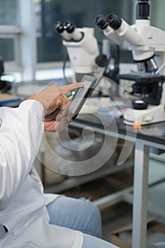 Close-up of a scientist using a handheld tablet in the laboratory