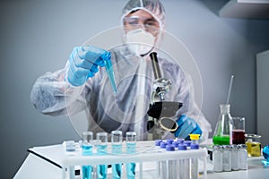 Close-up of scientists hand in blue latex gloves examines samples chemical liquid in test tube in science laboratory