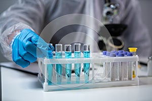 Close-up of scientists hand in blue latex gloves examines samples chemical liquid in test tube in science laboratory