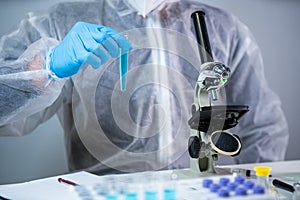 Close-up of scientists hand in blue latex gloves examines samples chemical liquid in test tube in science laboratory