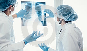 Close up. scientists in protective masks looking at an x-ray of the lungs .