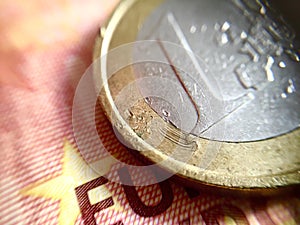 Close up of a scratched 1â‚¬ coin over a 10â‚¬ banknote