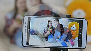 Close-up of the screen of the smartphone - two sisters lead a videoblog. Two teenage girls talking while looking at the