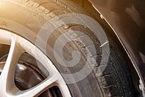 close up of screw nail puncturing car tire