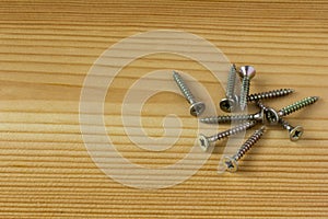 Close-up on screws, metal screws, iron screws, wood screws on wooden board