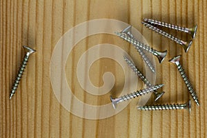 Close-up on screws, metal screws, iron screws, wood screws on wooden board