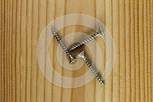 Close-up on screws, metal screws, iron screws, wood screws on wooden board