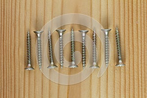 Close-up on screws, metal screws, iron screws, wood screws on wooden board