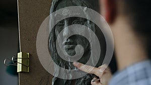 Close-up of Sculptor creating sculpture of human`s face on canvas in art studio