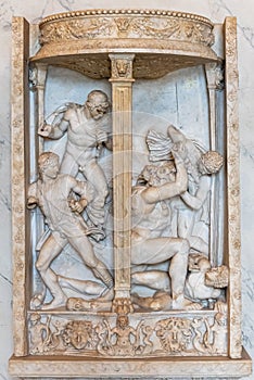 Close-up on sculptures carved in a marble wall representing a young menÂ´s fight
