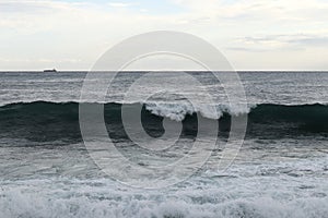 Close up of sea level while creating the perfect wave for surfers. The wave begins to flip and fall to the rest of the sea level.