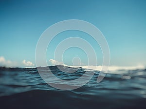 Close up of sea wave. Front view on beautiful sea wave on sandy beach. Summer sunny day, blue sky, water background. Blur effect