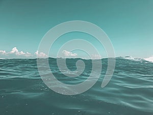 Close up of sea wave. Front view on beautiful sea wave on sandy beach. Summer sunny day, blue sky, water background