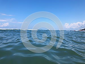 Close up of sea wave. Front view on beautiful sea wave on sandy beach. Summer sunny day, blue sky, water background