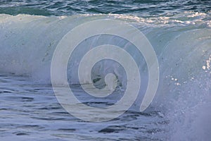 Close up of sea waves at sunset with orange light reflecting