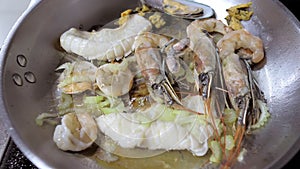 Close-up of seafood fried in a frying pan in hot oil. A professional chef cooks in the flambe style.Cooking a dish. A