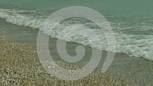 Close-up of the seashore. Calm waves of ocean water lapping the sandy beach.