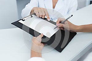 Close up. The secretary in a medical clinic helps the patient complete the necessary forms before starting treatment.