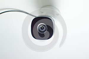 Close-up of a security camera mounted on a wall in a modern office, ready to be used