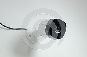 Close-up of a security camera mounted on a wall in a modern office, ready to be used