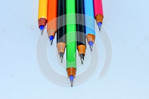 Close-up of a selection of Multi Colored boll point pens, stick together arranged in a row like bar graph on white background,