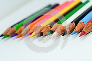 Close-up of a selection of Multi Colored pencils crayons, stick together arranged in a row line bar graph on white background,