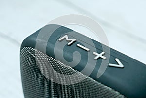 Close up and selective focus of bluetooth speaker button on white wooden background.