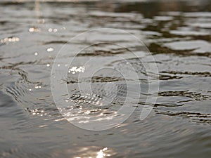 Close up and selective focus of flowing river surface with refelection of the evening sun