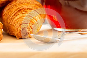 Close up and selective focus of Fresh croissants, spoon and honey jar over wooden board, breakfast, food background