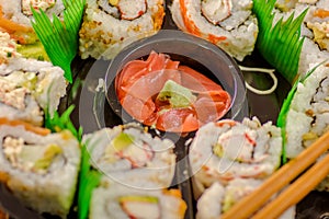 Close up of selective focus of large set of delicious japanese sushi rolls on a black plastic plate