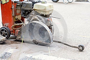 Close up and selective focus of the petrol powered road saw with dimond blade cutting asphalte road surface