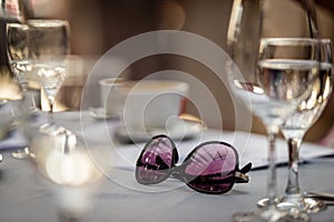 Close-up selective focus photography. On the table are sunglasses and wine glasses.