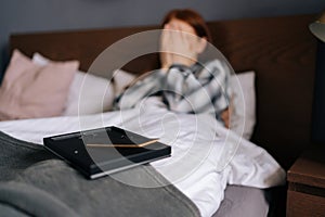 Close-up selective focus shot of picture frame on blurred backwound of crying grief-stricken young woman lying on bed
