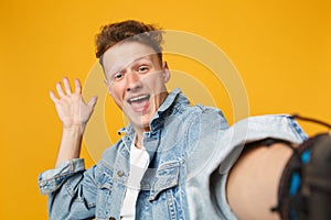 Close up selfie shot of excited young man in denim casual clothes keeping mouth wide open isolated on yellow orange