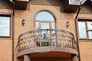 A close-up on semi-circled balcony with wrought iron railings, arched glass door
