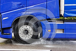 Close-up semi-trailer truck wheel driving fast Splashing Water on Highway, Risk of Aquaplaning on Wet Road. Detail view