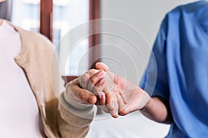 Close-up senior Asian woman hand with her caregiver helping hands, Caregiver visit at home. Home health care and nursing home