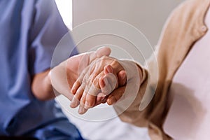 Close-up senior Asian woman hand with her caregiver helping hands, Caregiver visit at home. Home health care and nursing home