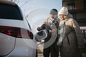 Close up of senior couple charging electric car.