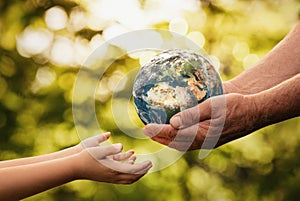 Senior hands giving planet earth to a child