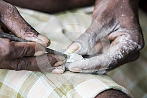 Close up of senior indian asian man sculptor carver hands working on his marble sculpture with chisel.