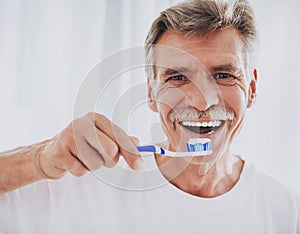 Close up. Senior Man Brushing Teeth in Bathroom.