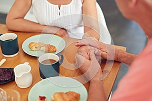 Close Up Of Senior Man Comforting Woman Suffering With Depression At Breakfast Table At Home