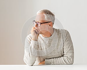 Close up of senior man in glasses thinking