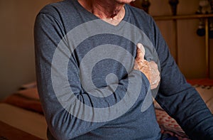 Close Up Of Senior Man With Health Issues At Home Clutching Chest In Pain