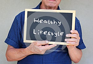 Close up of senior man holding a blackboard with the phrase good health equals good life