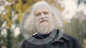 Close-up of senior man looking away smiling and turning to camera. Headshot of confident handsome Caucasian male retiree