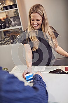 Close Up Of Senior Man Making Contactless Payment To Stylist In Salon With Credit Card