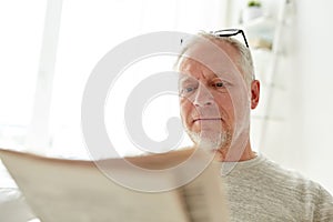 Close up of senior man reading newspaper at home