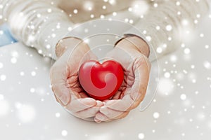 Close up of senior man with red heart in hands